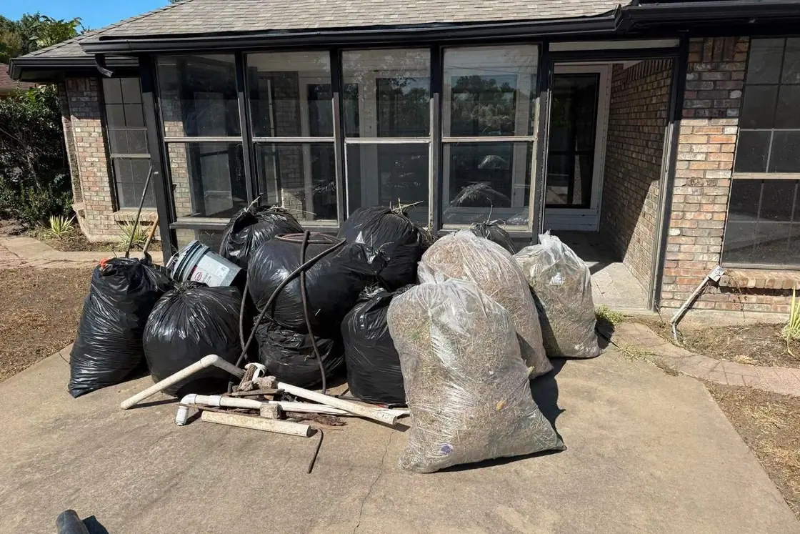 Bags of yard waste and old pipe gathered on a patio for haul-away